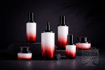 Red-to-white gradient acrylic skincare bottles and cosmetic jars with black caps, displayed on layered stands with open jar.
