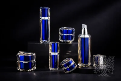 Aether blue faceted acrylic serum bottles and cosmetic jars, arranged on black risers with open bottle and reflective accents.