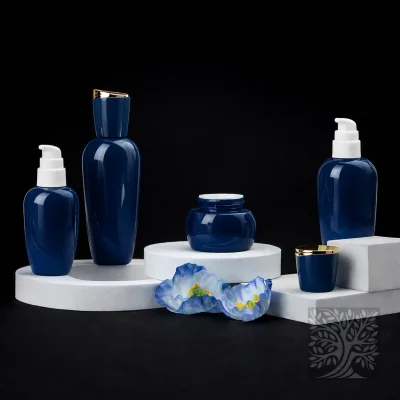 Gloss deep blue glass bottles and cosmetic jars with gold accents, arranged with floral detail in an Aurelius display.
