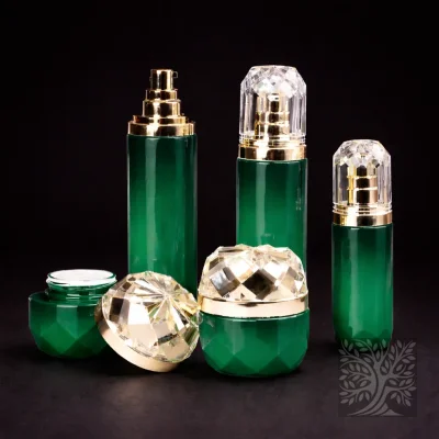 Emerald green faceted skincare bottles and jars with gold detailing and clear domed caps, arranged in a balanced grouping.
