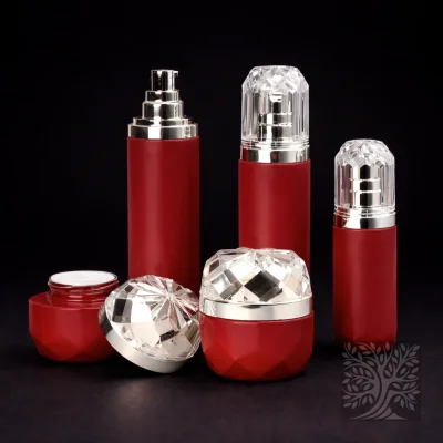 Matte red faceted bottles and cosmetic jars with gold pumps and clear caps, arranged in a bold cohesive packaging display.