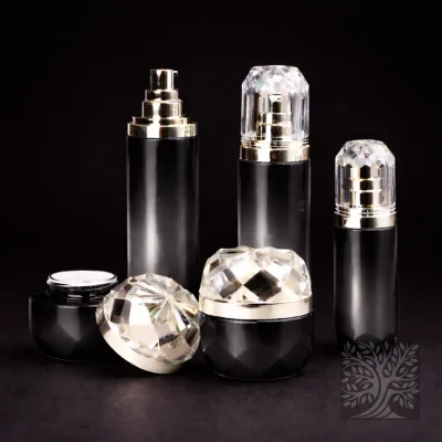 Gloss black faceted bottles and cosmetic jars with gold pumps and clear caps, styled in a sleek monochrome display.