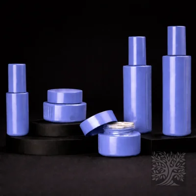 Gloss lavender glass packaging set with cylindrical skincare bottles and matching jars, arranged with one jar open on a platform.