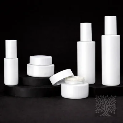 Gloss white skincare bottles and cosmetic jars with clean cylindrical forms, including an open jar, arranged on black stands.