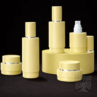 Pastel yellow cosmetic bottles and matching jars with silver accents, arranged in a soft-toned elevated product display.
