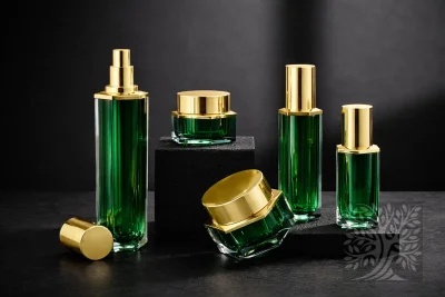 Emerald green acrylic skincare bottles and cosmetic jars with gold caps, arranged on black stands with open jar view