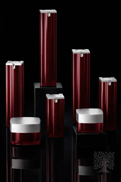 Deep red acrylic skincare bottles and jars with silver caps, presented in a balanced arrangement on dark platforms.