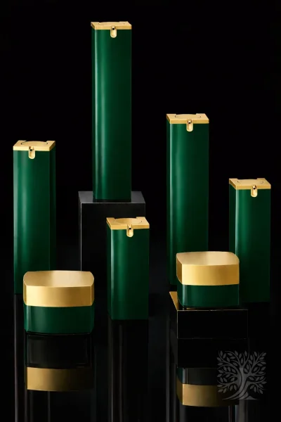 Emerald green skincare bottles and cosmetic jars with gold caps, arranged in a symmetrical elevated presentation.