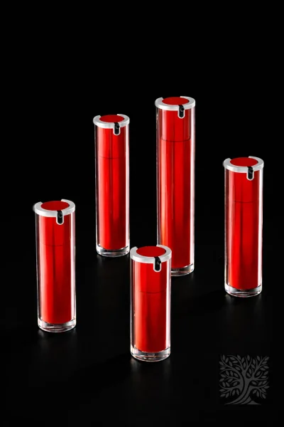 Red acrylic skincare bottles with silver caps and clear outer cylinders, arranged in varying heights against a dark background.