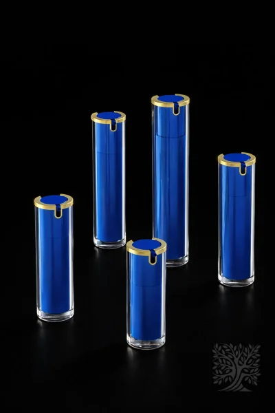 Cobalt blue acrylic serum bottles with gold collars and clear cylindrical outer layers, presented in a balanced grouping.