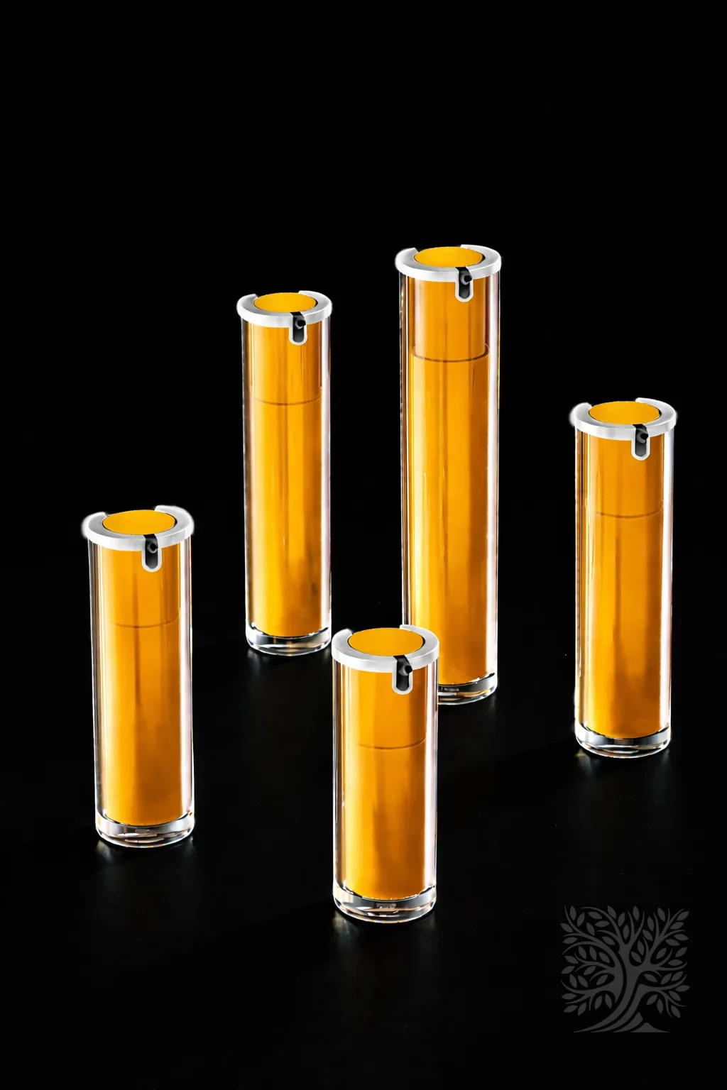 Bright yellow acrylic serum bottles with gold caps and clear cylindrical exteriors, displayed in a bold color arrangement.