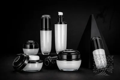 Glossy black and white acrylic skincare bottles and cosmetic jars with black caps, arranged on dark platforms with minimalist styling.