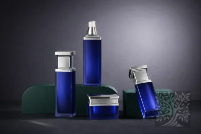 Cobalt blue acrylic skincare bottles and cosmetic jars with silver caps, arranged on stands with varied bottle heights.