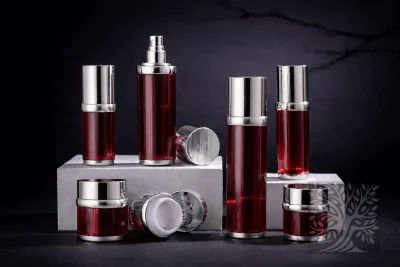 Deep red ribbed acrylic skincare bottles and cosmetic jars with silver caps, arranged on white blocks with open jar display.